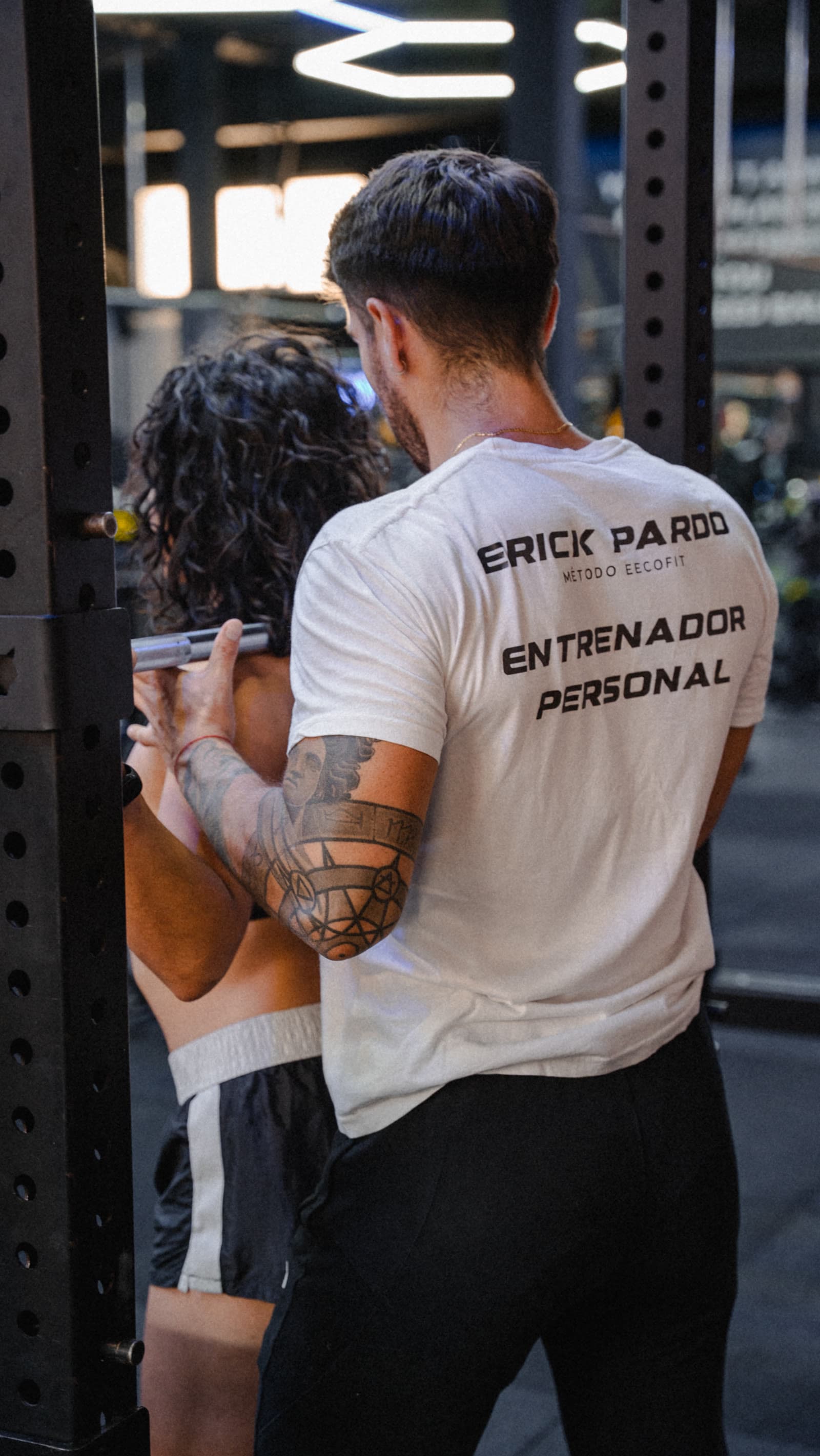 Erick supervisa de cerca un ejercicio con barra en el gimnasio